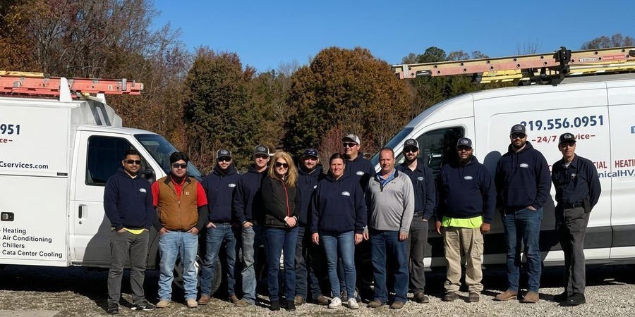 the mechanical hvac team stanging outside infromt of their van and truck