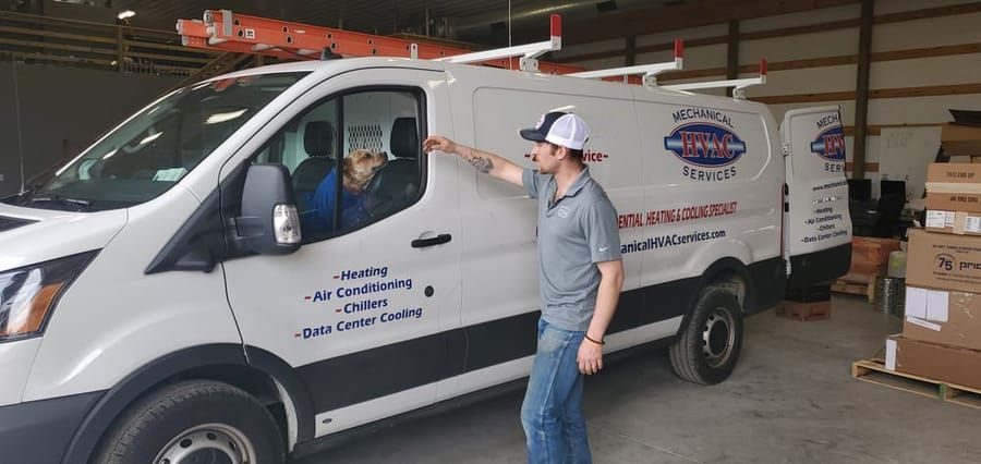 Mechanical Technician petting dog in the front seat of a van ready to go to a commercial air filtration service.