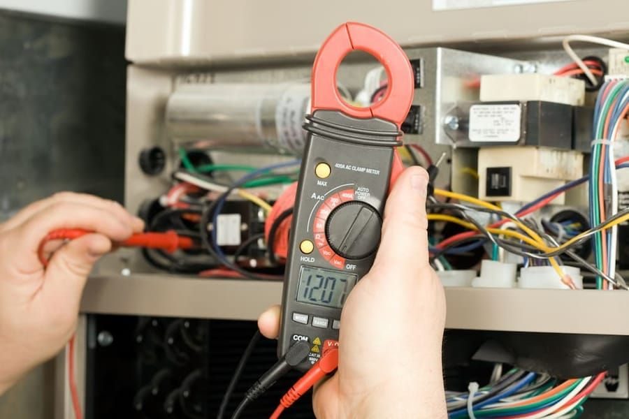 HVAC technician testing electrical components during furnace repair service.