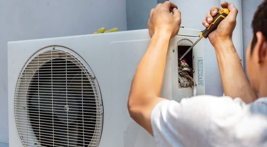 HVAC technician repairing outdoor heat pump unit during heat pump repair service.