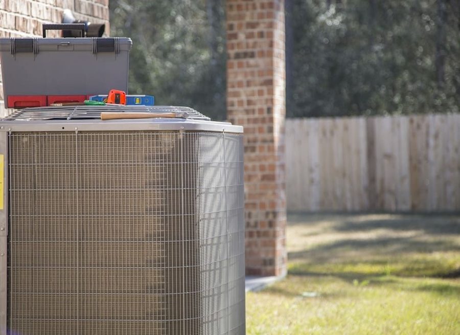Outdoor air conditioning unit with technician's tools on top it; AC repair service.